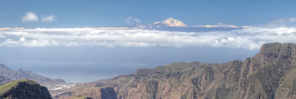 Panoramaausblick auf Teneriffas Teide von den Höhenwegen Gran Canarias, mit schneebedecktem Gipfel, Wolkenmeer und markanter Berglandschaft – Highlight vieler Wanderungen im Inselinneren.